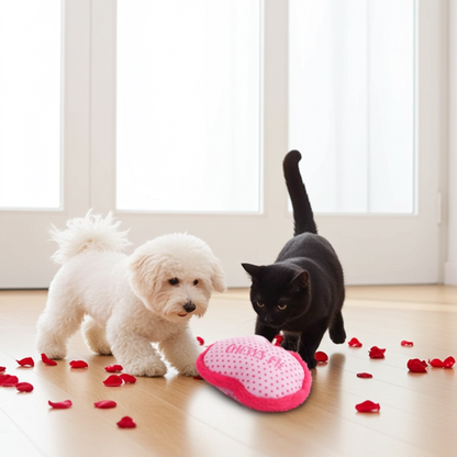 White dog and black cat playing with a pink toy on a wooden floor.